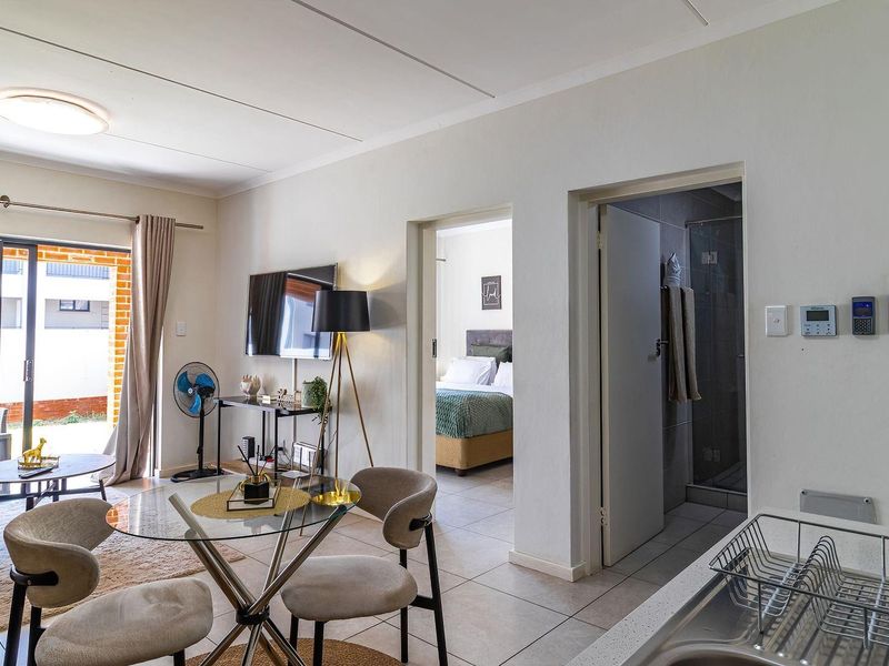 Open-plan living area featuring tiled flooring, a sliding door to the patio, and direct access to the bedroom and bathroom.