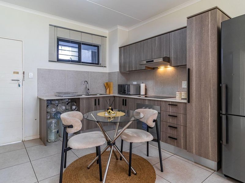 Modern kitchen featuring wood-grain cabinetry, stone-look countertops, integrated appliances, and tiled flooring, offering a functional and contemporary cooking space.