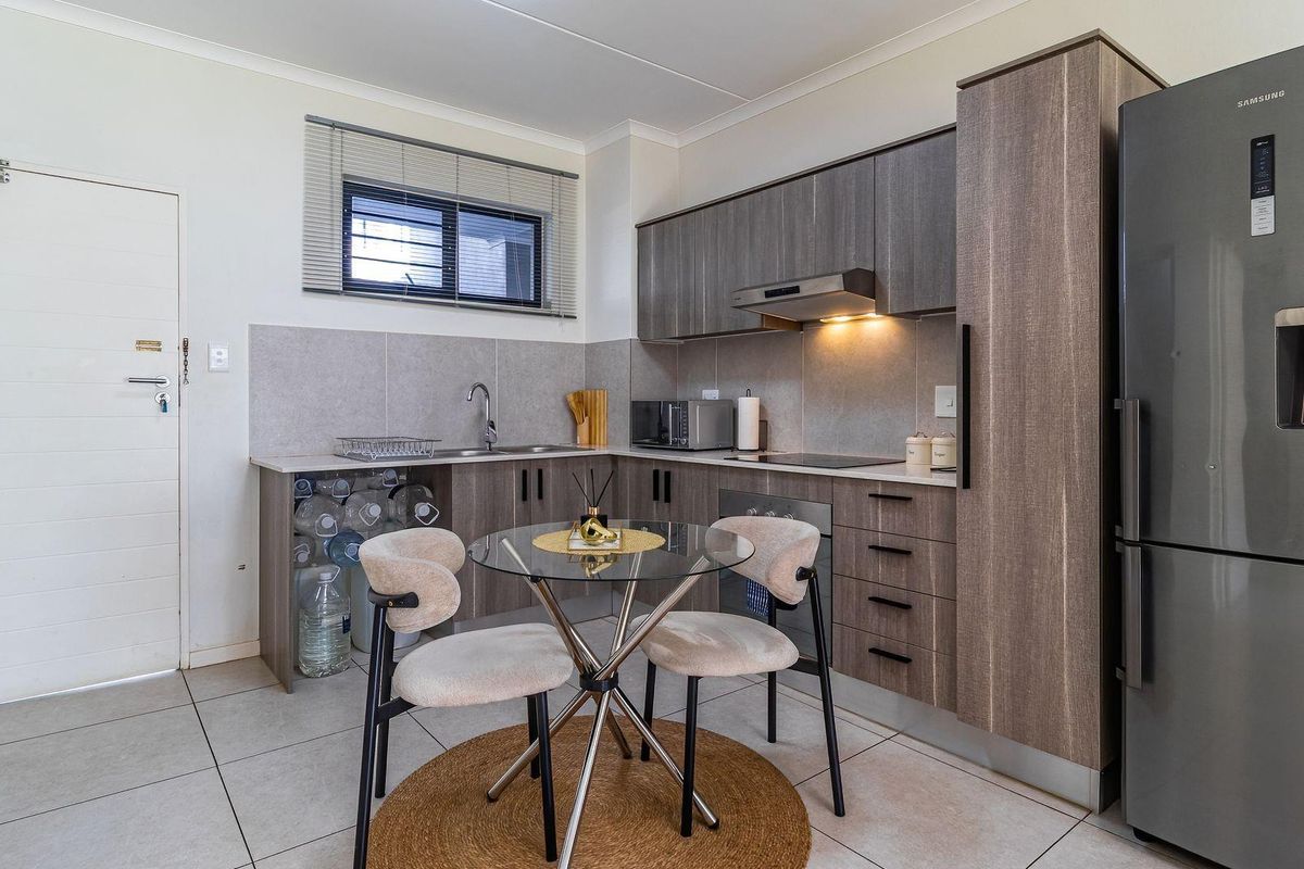 Modern kitchen featuring wood-grain cabinetry, stone-look countertops, integrated appliances, and tiled flooring, offering a functional and contemporary cooking space.
