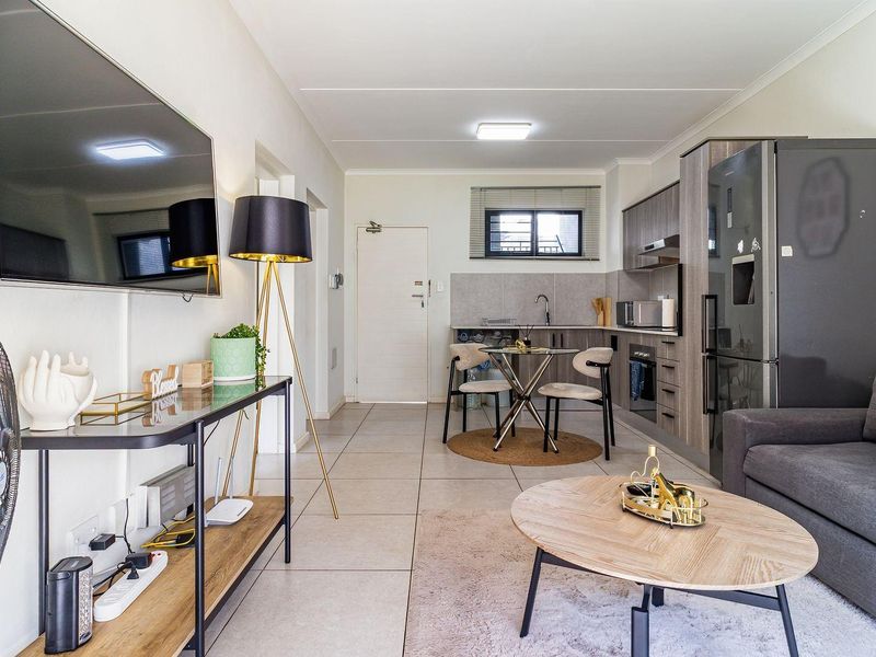 An open-plan living and kitchen area featuring modern cabinetry, tiled flooring, and a functional layout suitable for compact apartment living.