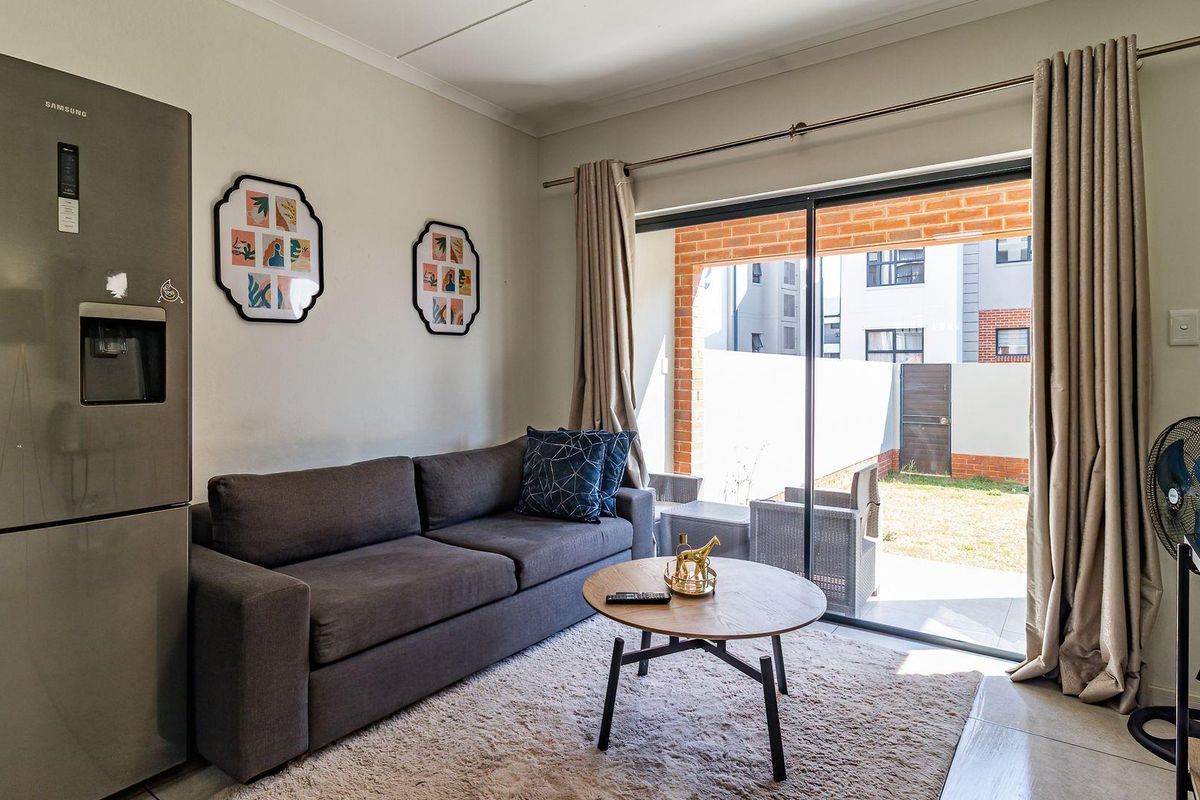 A bright living room featuring tiled flooring and a large sliding glass door that provides direct access to an outdoor patio area.