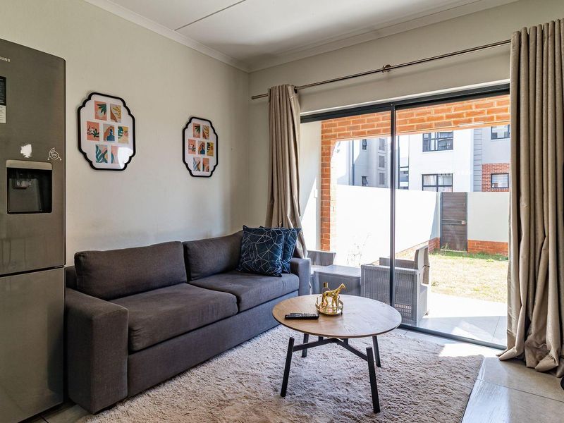 A bright living room featuring tiled flooring and a large sliding glass door that provides direct access to an outdoor patio area.