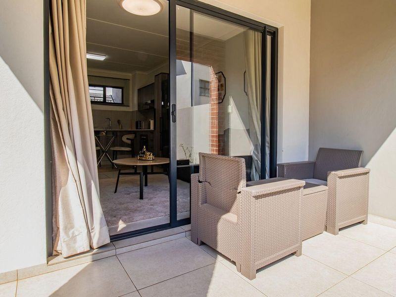 A covered patio area featuring tiled flooring and a large sliding glass door providing access to the interior living space.