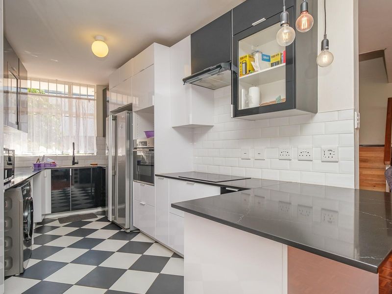 Modern kitchen featuring high-gloss cabinetry, stone countertops, subway tile backsplash, and integrated appliances with a distinctive checkerboard floor.