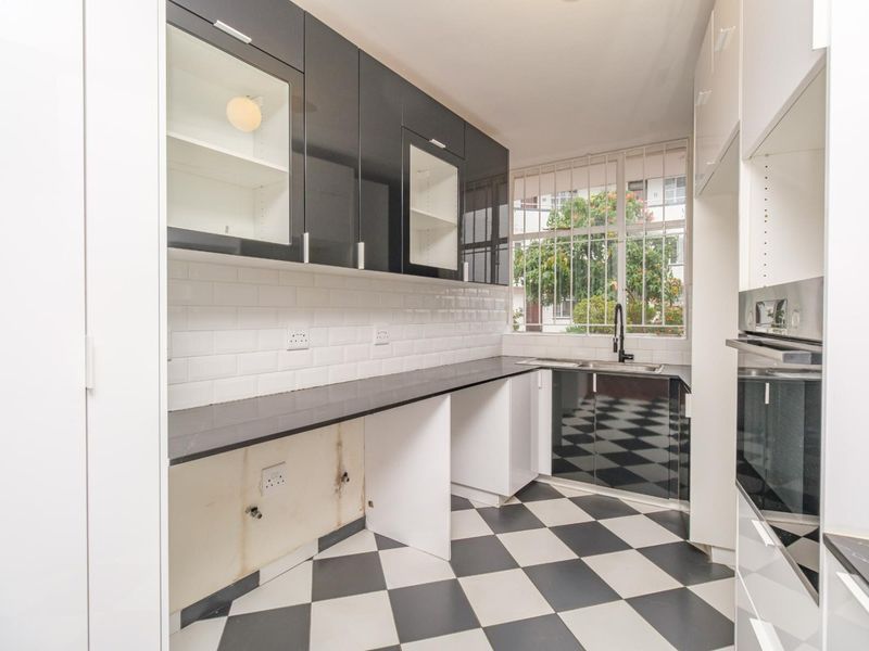 A modern kitchen featuring high-contrast black and white cabinetry, subway tile backsplash, and checkered flooring, currently awaiting final appliance installation.