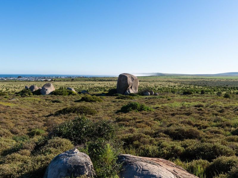A scenic view of the vacant residential land featuring natural rock formations and distant coastal landscape.