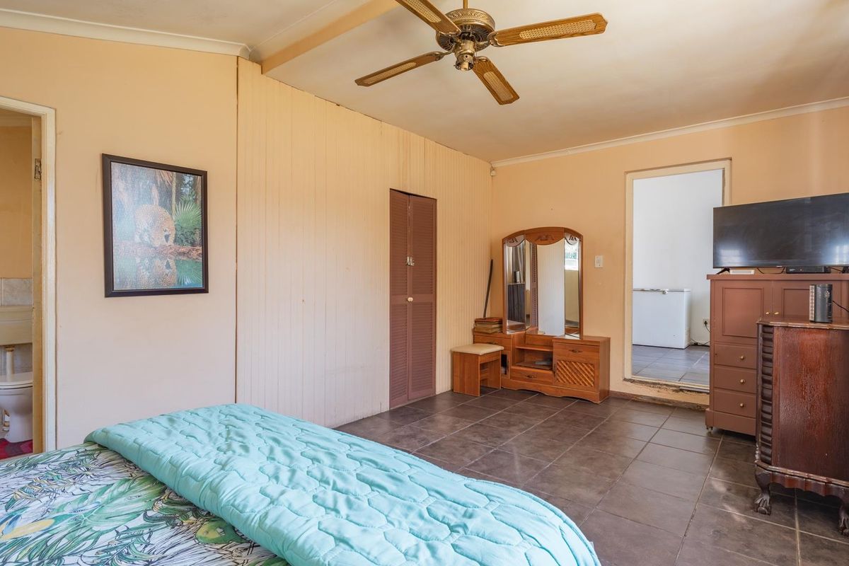 Bedroom featuring tiled flooring, a ceiling fan, and an en-suite bathroom. The space offers functional layout with built-in storage.
