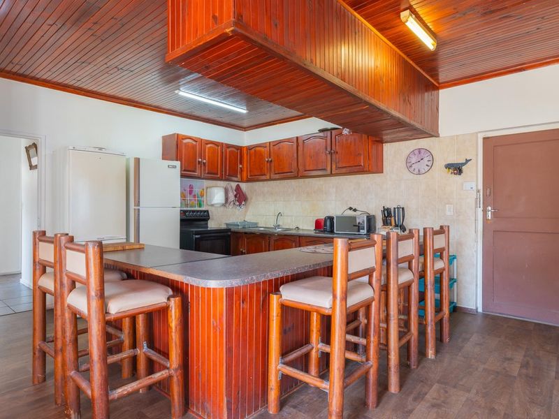A dated kitchen featuring wooden cabinetry, a breakfast bar, and wood-paneled ceilings, offering significant potential for a modern renovation.