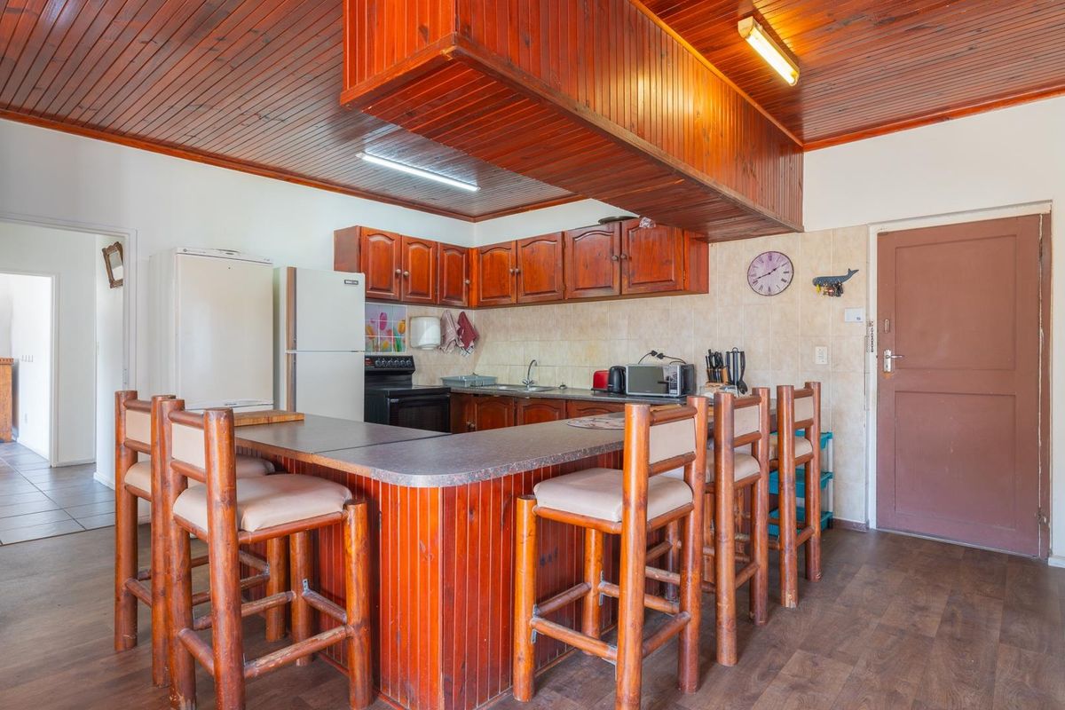 A dated kitchen featuring wooden cabinetry, a breakfast bar, and wood-paneled ceilings, offering significant potential for a modern renovation.