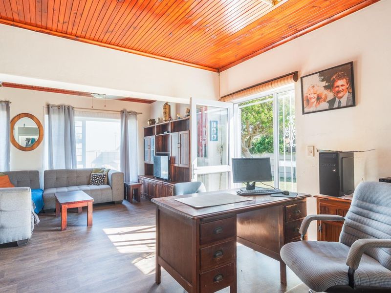 Open plan living area featuring timber ceilings, laminate flooring, and direct access to the garden through a sliding glass door.
