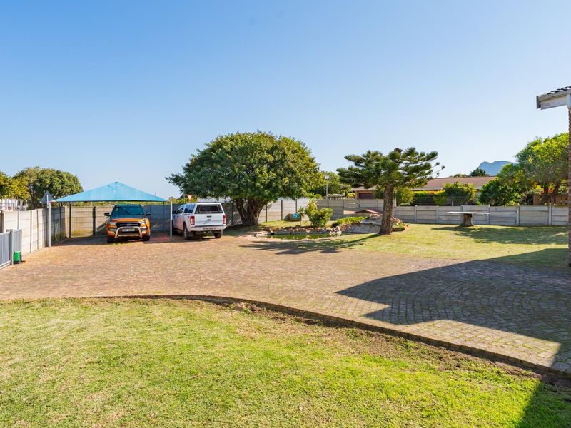 Spacious front yard featuring a paved driveway, secure boundary walling, and a shade cloth carport area.