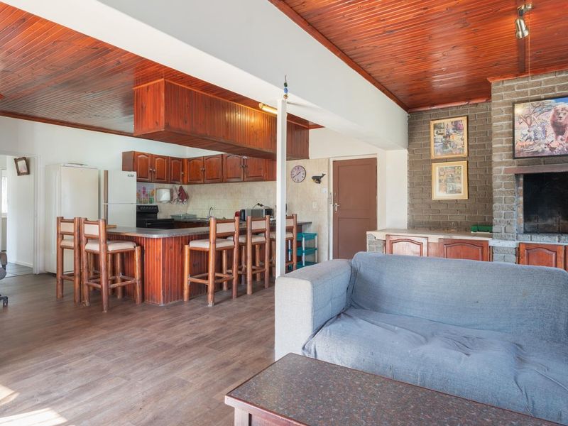 Open-plan living and kitchen area featuring a timber-clad ceiling, brick fireplace, and a functional breakfast bar with built-in cabinetry.