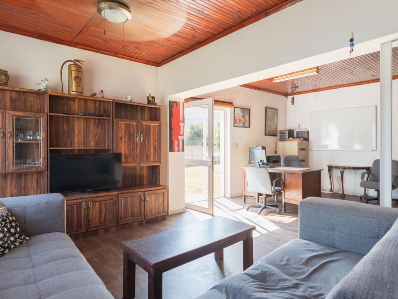 Open plan living and office area featuring a timber tongue and groove ceiling and built-in wooden cabinetry with direct access to the exterior.