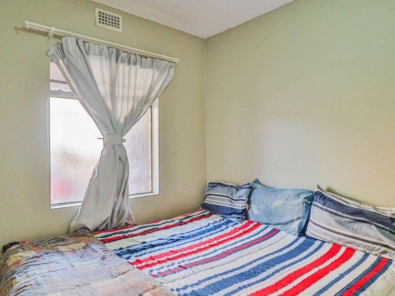 A standard bedroom featuring a window with natural light and a ceiling air vent.