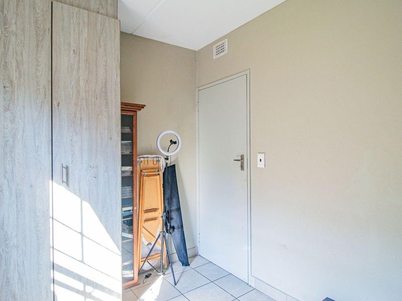 A bedroom featuring built-in cupboards with a light wood finish and tiled flooring.