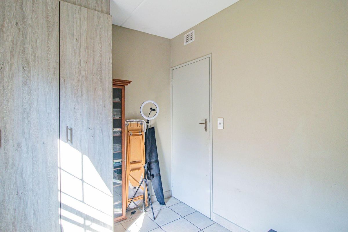 A bedroom featuring built-in cupboards with a light wood finish and tiled flooring.
