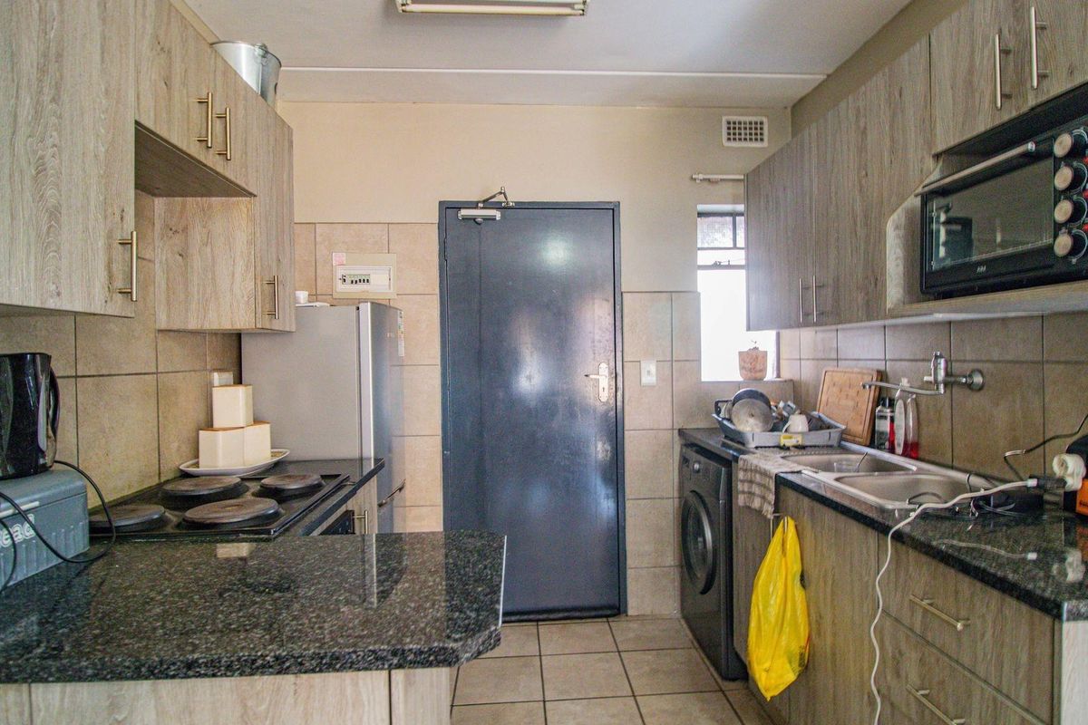 A functional kitchen featuring granite countertops, built-in cabinetry, an electric hob, and a built-in microwave with tiled flooring and backsplash.