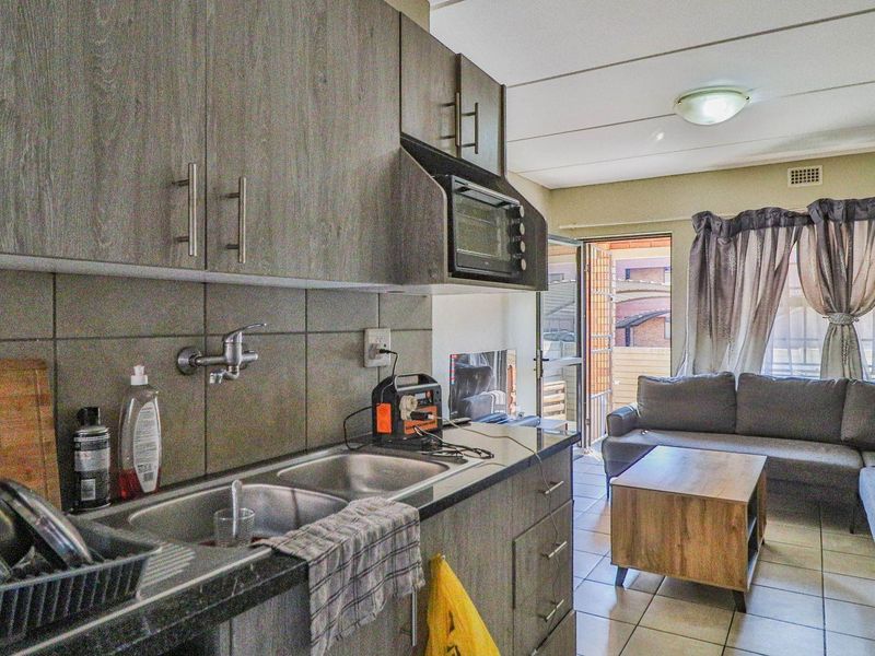 Open-plan kitchen and living area featuring modern grey cabinetry, tiled flooring, and direct access to an outdoor balcony space.