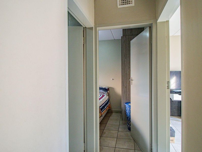 A functional hallway connecting multiple rooms, featuring tiled flooring and standard internal door frames.