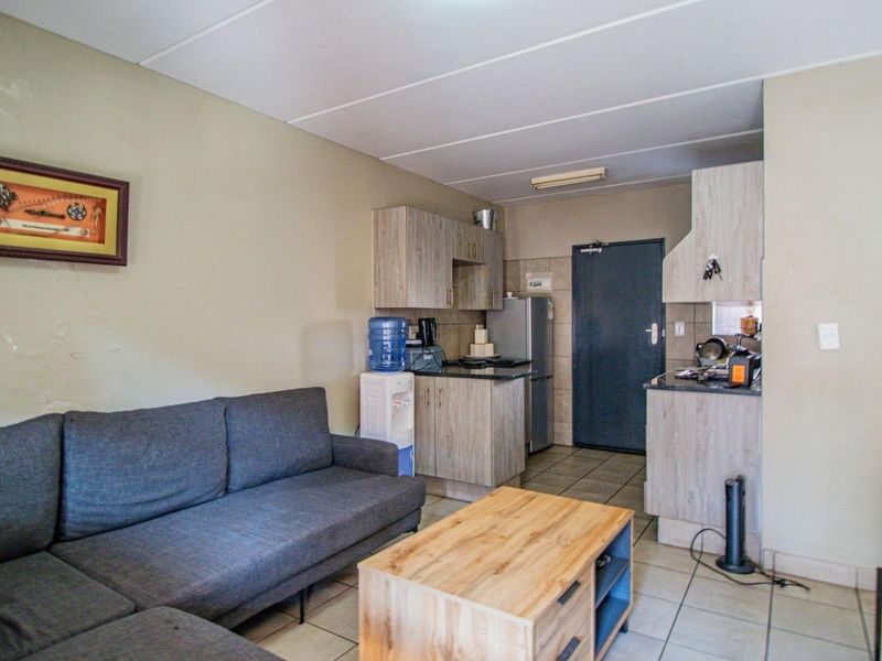 Open-plan living area featuring tiled flooring and a compact kitchen with built-in cabinetry.