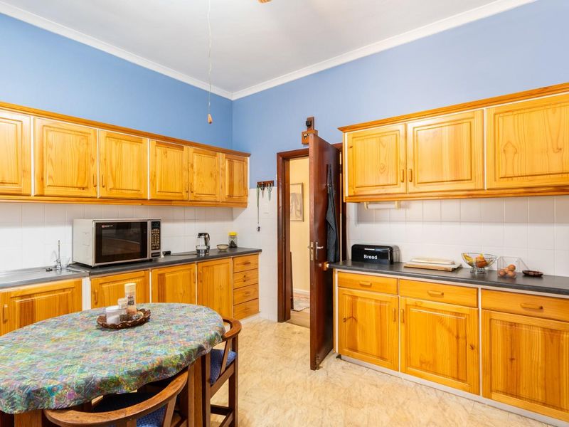 A functional kitchen featuring extensive wooden cabinetry, laminate countertops, a tiled backsplash, and a built-in microwave, offering a classic and practical layout.