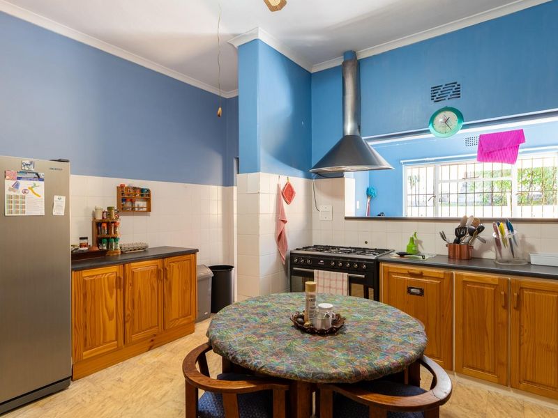 A functional kitchen featuring wooden cabinetry, a gas stove with extractor fan, and tiled splashbacks, offering a practical layout for daily cooking.