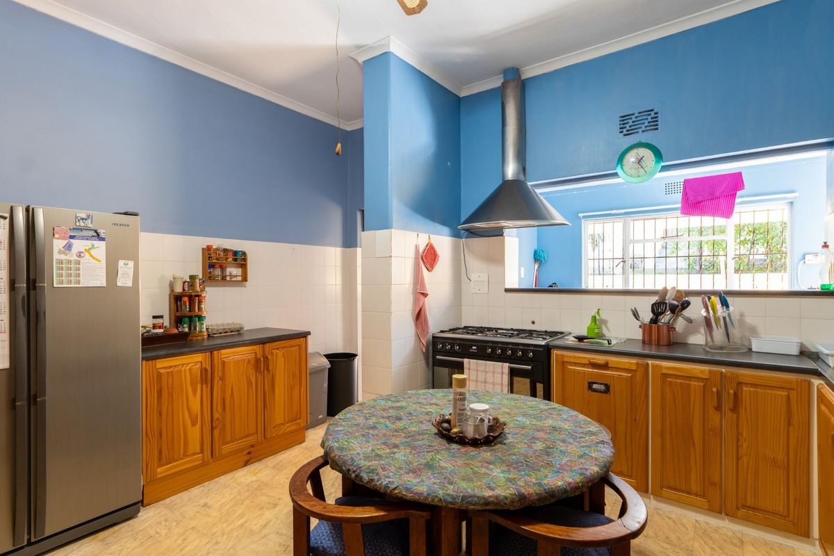 A functional kitchen featuring wooden cabinetry, a gas stove with extractor fan, and tiled splashbacks, offering a practical layout for daily cooking.