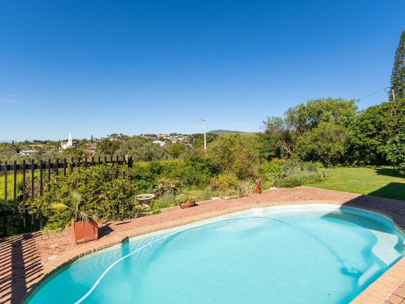 Outdoor pool area featuring brick paving, a swimming pool, and a landscaped garden with scenic views of the surrounding neighborhood.