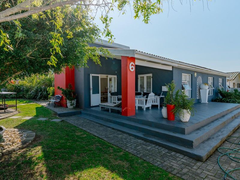 A well-maintained rear exterior view featuring a spacious covered patio, paved walkway, and established garden area.