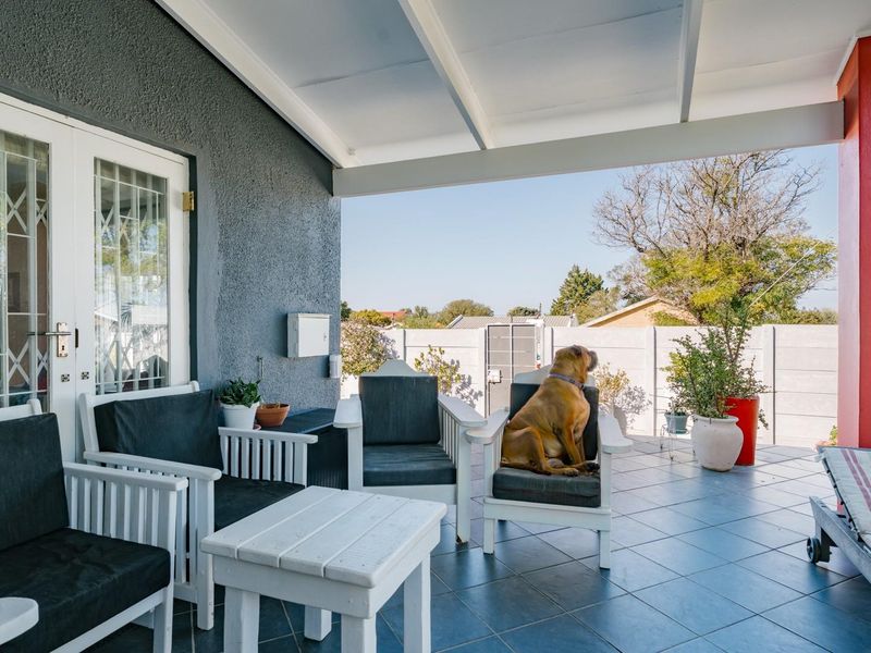 A covered outdoor patio area featuring tiled flooring and direct access to the garden, providing a functional space for outdoor relaxation.