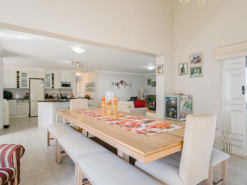 Spacious open-plan living and dining area featuring a modern kitchen with built-in cabinetry and seamless access to the outdoor patio through sliding doors.