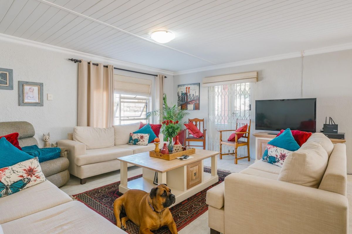 A comfortable living room featuring a tongue and groove ceiling, louver windows, and a security gate leading to the exterior.