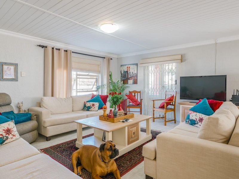 A comfortable living room featuring a tongue and groove ceiling, louver windows, and a security gate leading to the exterior.
