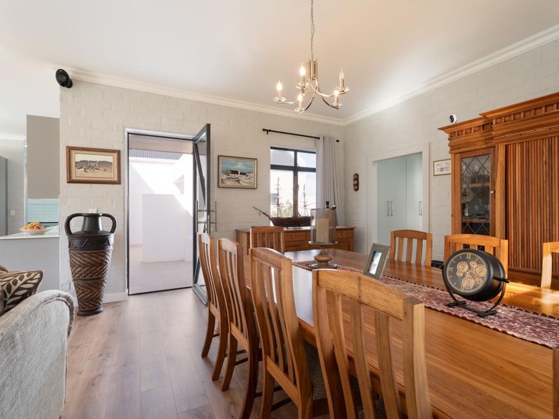 Spacious open-plan living and dining area featuring laminate flooring, painted brick walls, and direct access to an outdoor patio space.