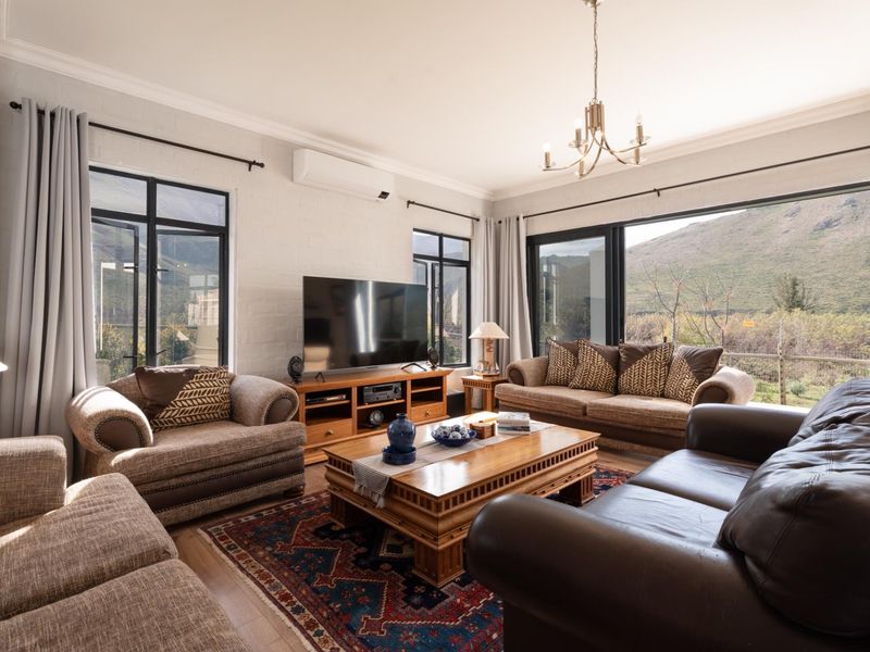 Spacious living room featuring large black-framed windows, sliding glass doors with mountain views, and a wall-mounted split-system air conditioner.