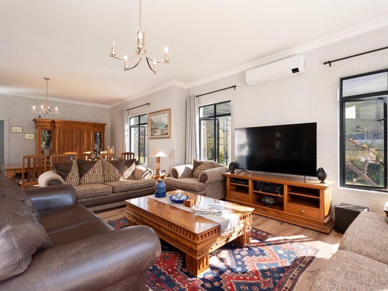 Spacious open-plan living and dining area featuring painted brick walls, large metal-framed windows, and a wall-mounted air conditioning unit.