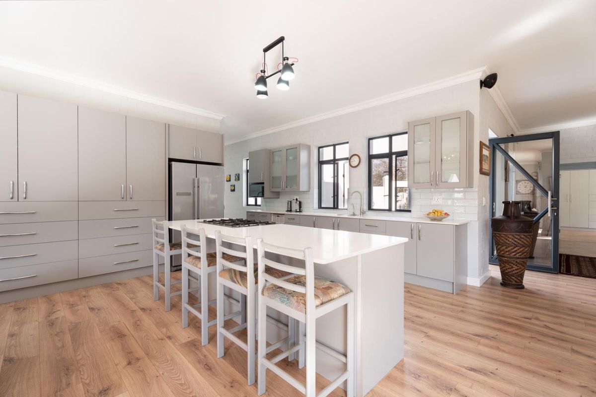 Modern, well-appointed kitchen featuring a central island with gas hob, stone countertops, ample cabinetry, and stylish laminate flooring in a bright, open layout.