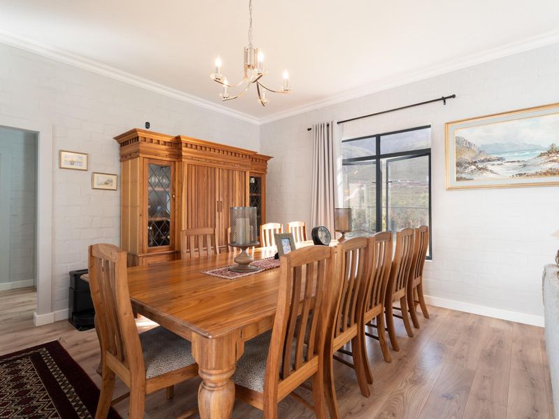 A well-maintained dining room featuring laminate flooring, painted brick walls, and a classic chandelier, offering a warm and inviting atmosphere.