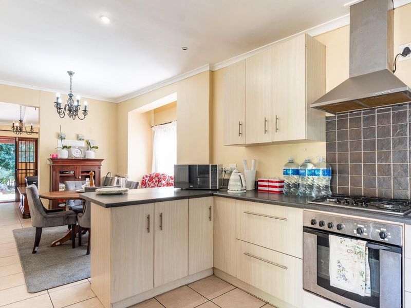 Open-plan kitchen and dining area featuring light wood-finish cabinetry, gas hob, built-in oven, and tiled flooring throughout.