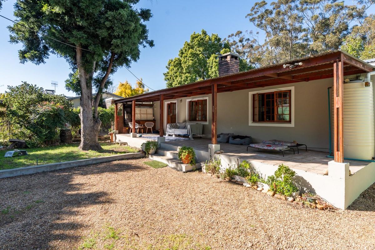 A spacious rear covered patio featuring a brick chimney, timber pergola structure, and direct access to the garden and gravel yard area.