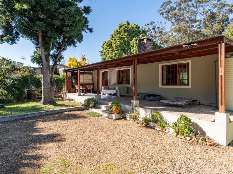 A spacious rear covered patio featuring a brick chimney, timber pergola structure, and direct access to the garden and gravel yard area.