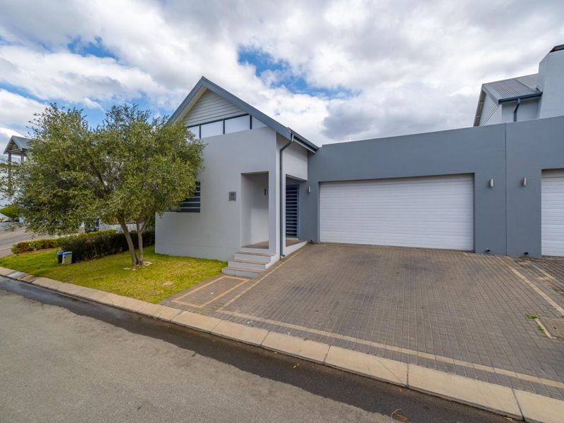 Modern residential facade featuring a paved driveway, double garage, and a covered entrance with contemporary architectural styling.