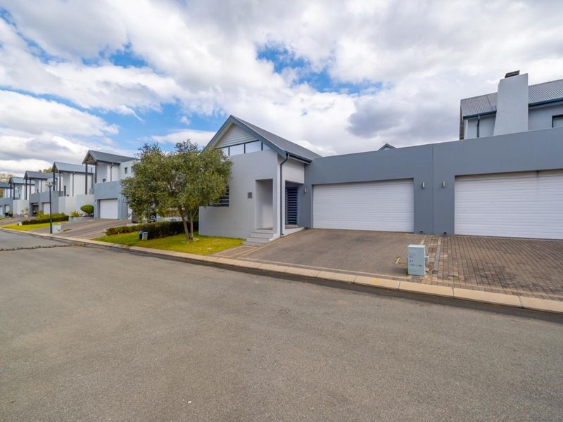 Front exterior view of a modern residential property featuring a double garage, paved driveway, and well-maintained facade in a quiet street setting.