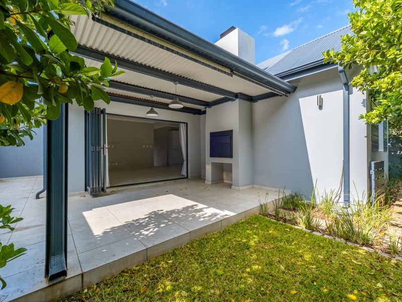 A covered patio featuring tiled flooring, a built-in braai, and folding doors providing seamless access to the interior living space.