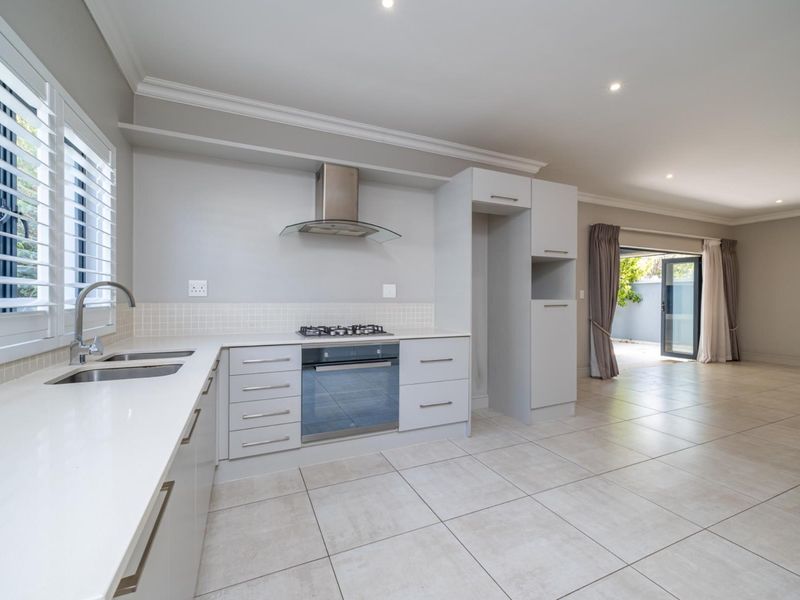 Modern open-plan kitchen featuring sleek cabinetry, quartz countertops, integrated appliances, and tiled flooring, flowing seamlessly into the adjacent living area.