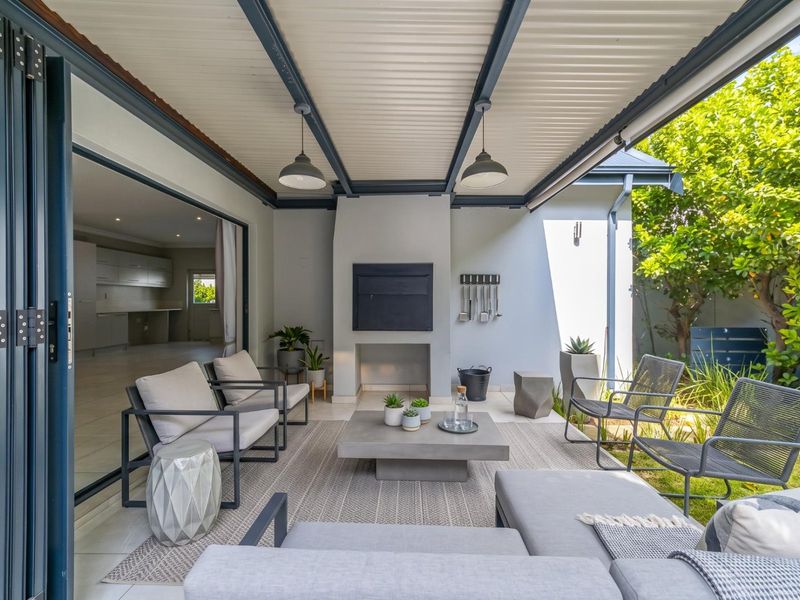 A modern covered patio featuring a built-in fireplace, tiled flooring, and folding glass doors that provide seamless access to the interior living space.