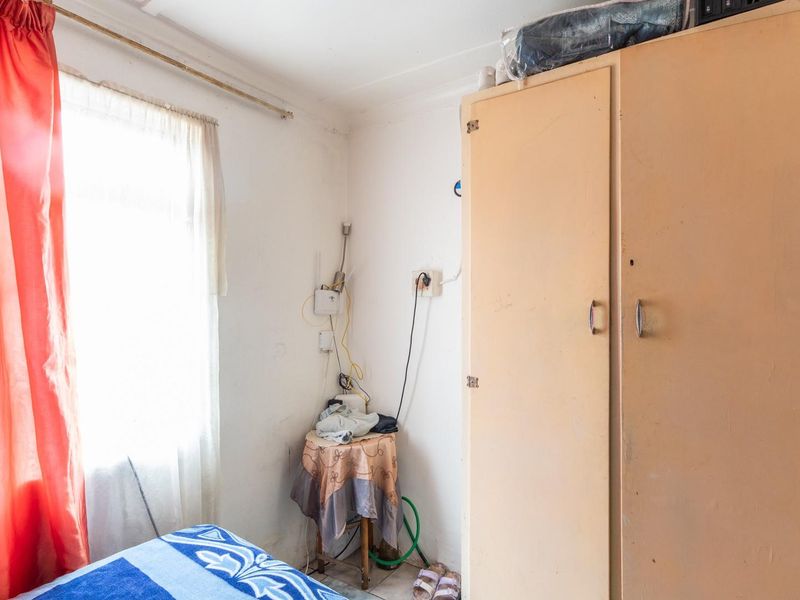 A bedroom featuring a built-in wardrobe and natural light from a window, requiring cosmetic updates to improve the overall finish and aesthetic appeal.
