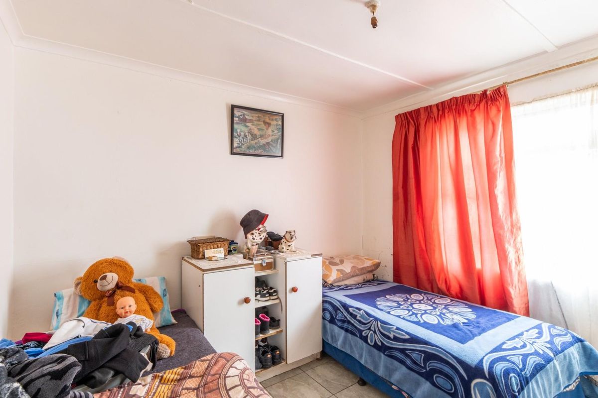 A functional bedroom featuring tiled flooring and a window with a curtain rail, offering a simple and practical living space.