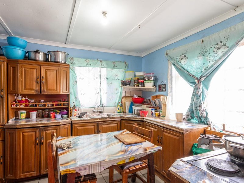 A dated kitchen featuring wooden cabinetry, laminate countertops, and a functional layout, offering significant potential for a modern renovation and aesthetic update.