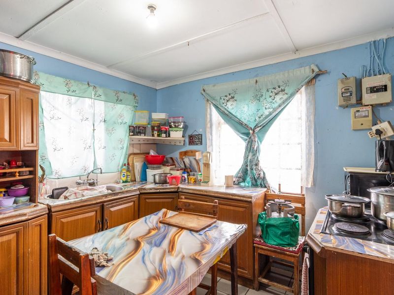 A dated kitchen featuring wooden cabinetry, laminate countertops, and a built-in hob, offering significant potential for modernization and renovation.